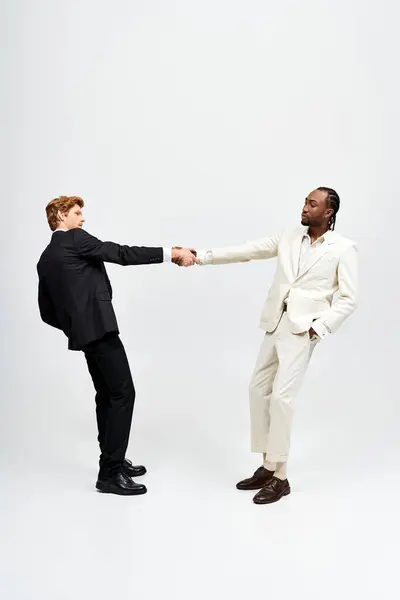 Zwei multikulturelle Männer in eleganten Anzügen beim Händeschütteln. — Stockfoto