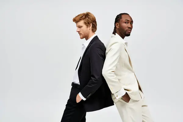 Hombres multiculturales guapos en trajes elegantes posando lado a lado. - foto de stock