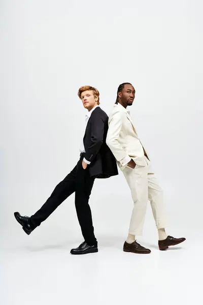 Двоє красивих мультикультурних чоловіків у костюмах позують пліч-о-пліч стильно. — стокове фото