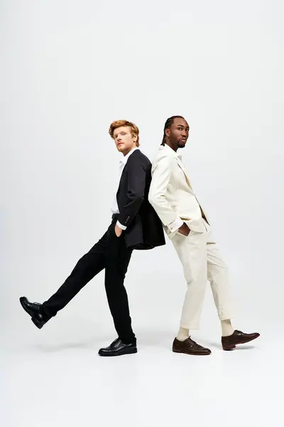 Two handsome multicultural men in suits posing side by side in a stylish manner. — Stock Photo
