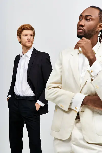 Dos hombres multiculturales en trajes elegantes de pie lado a lado. - foto de stock