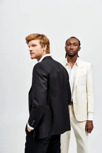 Two elegant multicultural men in suits standing side by side. — Stock Photo