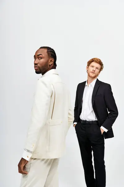 Two handsome men, one multicultural, stand elegantly in suits. — Stock Photo