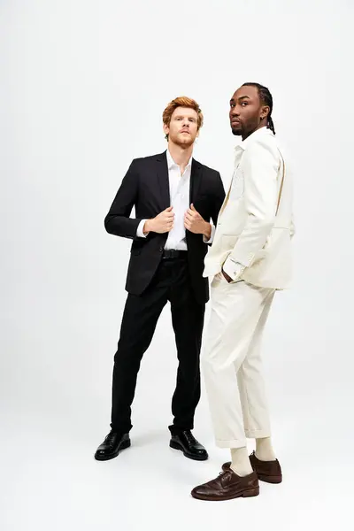 Двоє стильних чоловіків у костюмах стоять плечем до плеча. — стокове фото