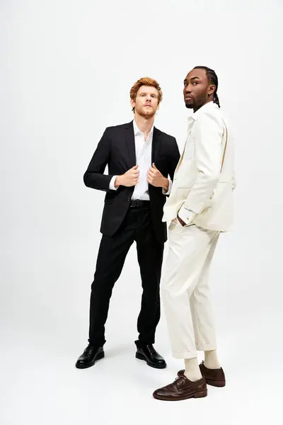 Two stylish men in suits stand shoulder to shoulder. — Stock Photo