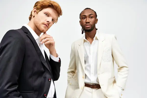Zwei gutaussehende multikulturelle Männer in schicken Anzügen stehen überzeugend zusammen. — Stockfoto