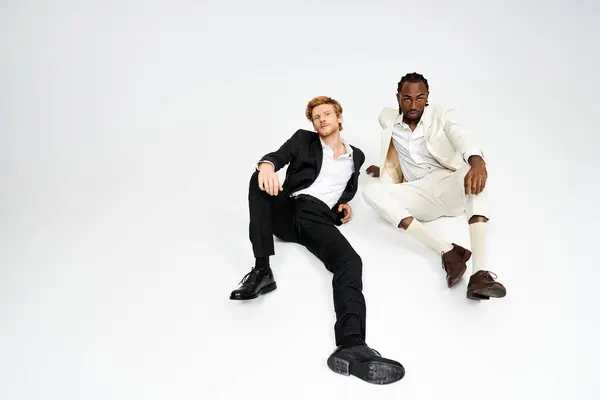 Two multicultural men with elegant style sitting side by side. — Stock Photo