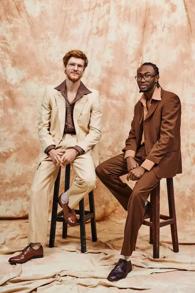 Two multicultural men in stylish suits sit closely together. — Stock Photo