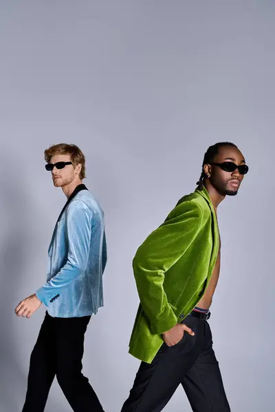 Two handsome multicultural men in dapper style walking across a gray background. — Stock Photo