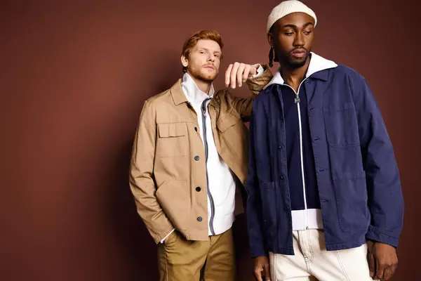 Zwei stylische multikulturelle Männer stehen gemeinsam vor einer braunen Wand. — Stockfoto