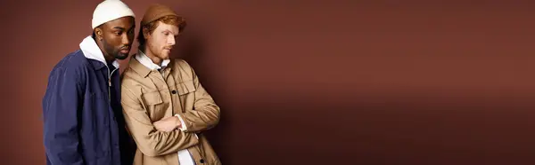 Stylish multicultural men strike a pose before a rustic brown wall. — Stock Photo