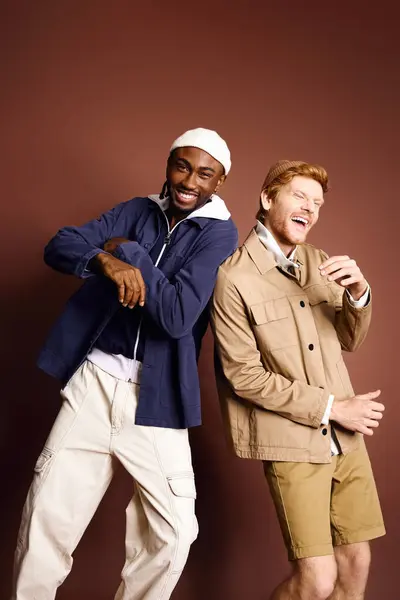 Deux hommes multiculturels avec une tenue élégante debout l'un à côté de l'autre devant un mur brun. — Photo de stock