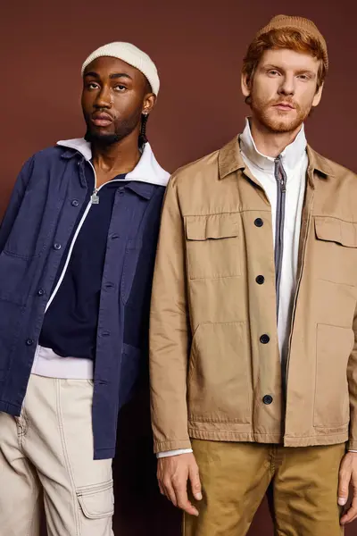 Dos hombres de moda de diferentes culturas de pie uno al lado del otro en chaquetas con estilo. - foto de stock