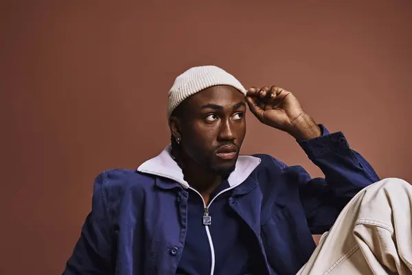 Молодий афроамериканський чоловік викриває стиль у синій куртці та білому капелюсі. — стокове фото