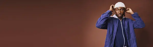 A handsome young African American man wearing a blue jacket and white hat. — Stock Photo