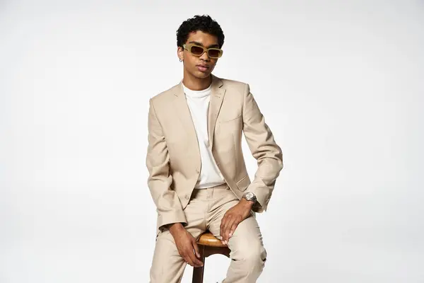 Handsome African American man in stylish sunglasses, sitting on stool. — Stock Photo