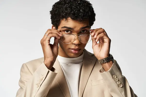 Young man in tan suit putting on stylish glasses. — Stock Photo