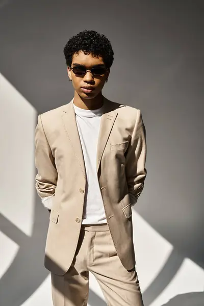 A handsome African American man in a tan suit posing in front of a white wall. — Stock Photo