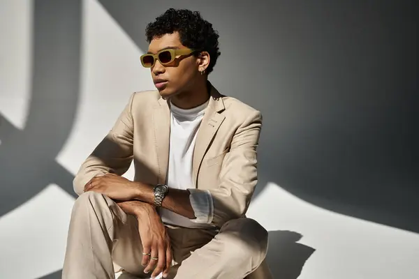 Um jovem homem afro-americano elegante em um terno bege e óculos de sol na moda. — Fotografia de Stock
