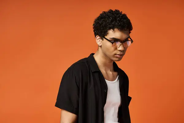 Handsome African American man in glasses against vibrant orange background. — Stock Photo