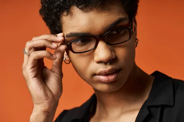 Handsome young man in glasses striking a pose against an orange backdrop — Stock Photo