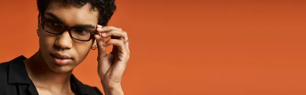 A stylish young man wearing glasses on a bright orange background. — Stock Photo