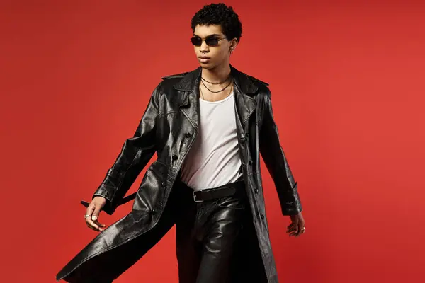 A man exudes coolness in a leather trench coat and sunglasses. — Stock Photo