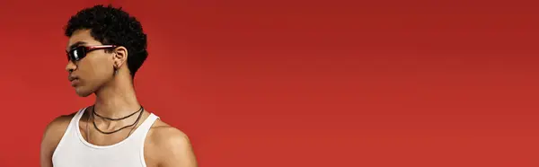 African American man in white tank top and sunglasses poses confidently against vibrant red backdrop. — Stock Photo