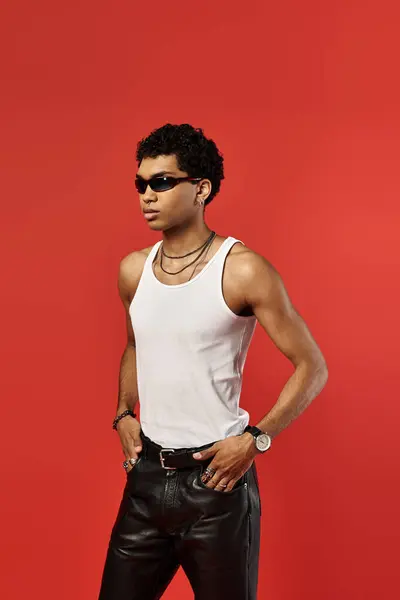 Handsome African American man in stylish sunglasses, dressed in white tank top and leather pants. — Stock Photo