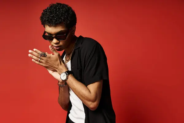 Красивий чоловік з сонцезахисними окулярами і чорною сорочкою вражає позу. — стокове фото