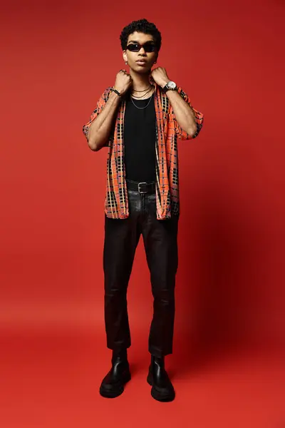 Handsome African American man in a shirt and black pants poses confidently on a bright red background. — Stock Photo