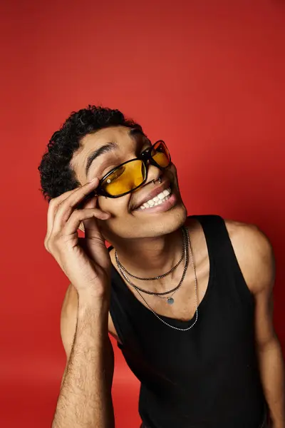Handsome African American man wearing sunglasses on a bright red background. — Stockfoto