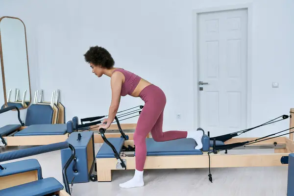 Woman in pink top exercises on rowing machine. — Stock Photo