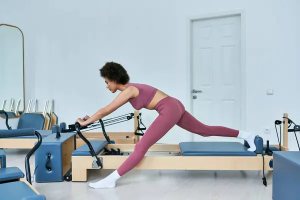 Жінка в рожевому верху і легінси енергійно виконує вправи. — стокове фото