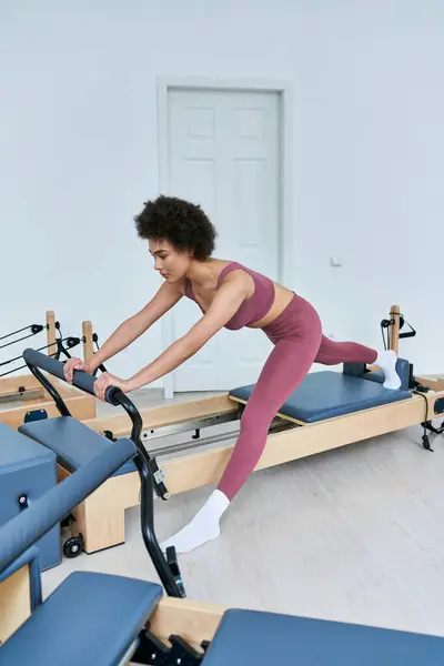 A woman in stylish attire cycling on a stationary exercise machine. — Stock Photo