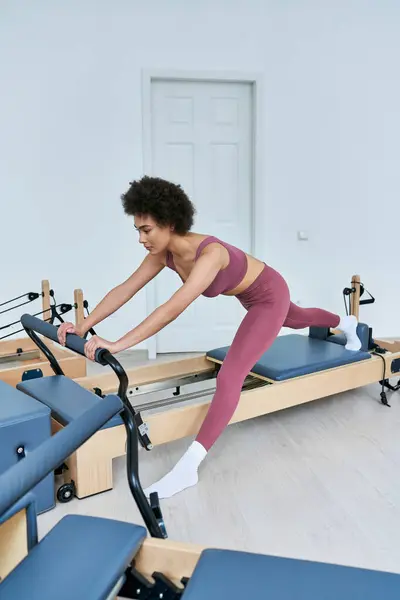 Eine Frau in stylischer Kleidung radelt auf einem stationären Trainingsgerät. — Stockfoto