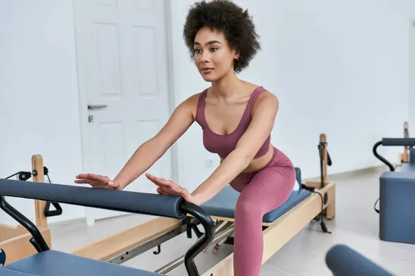 Woman in pink top and leggings gracefully exercising. — Stock Photo