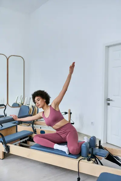 Une femme en haut rose et pantalon rose effectue gracieusement des exercices. — Photo de stock