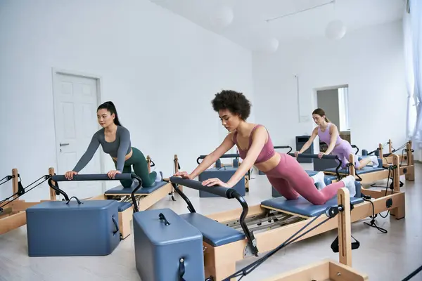 Groupe diversifié de femmes engagées dans une classe de pilates, concentrées et déterminées. — Photo de stock