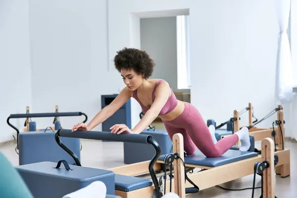 Una mujer con un top rosa hace ejercicios en un gimnasio. - foto de stock