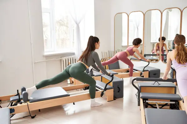 Mujeres enérgicas que participan en una sesión de pilates dinámicos en el gimnasio. - foto de stock
