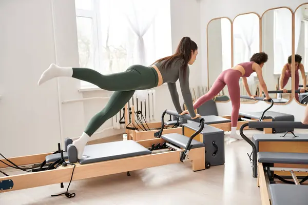 Grupo de mujeres disfrutando de una sesión de pilates dinámica en un gimnasio. - foto de stock