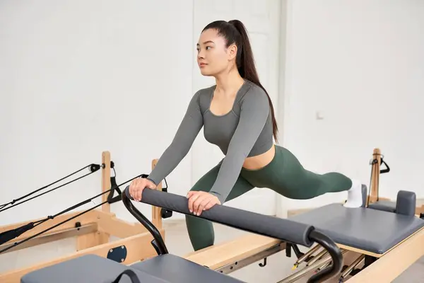 A sporty woman in gray shirt, green pants on Pilates lesson. — Stock Photo