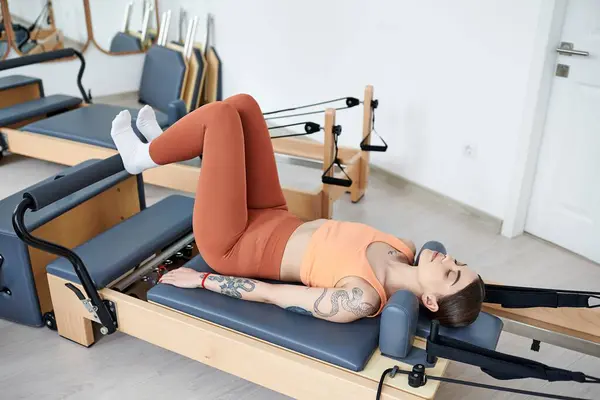 Uma mulher esportiva, focada em engajar seus músculos durante uma aula de pilates. — Fotografia de Stock