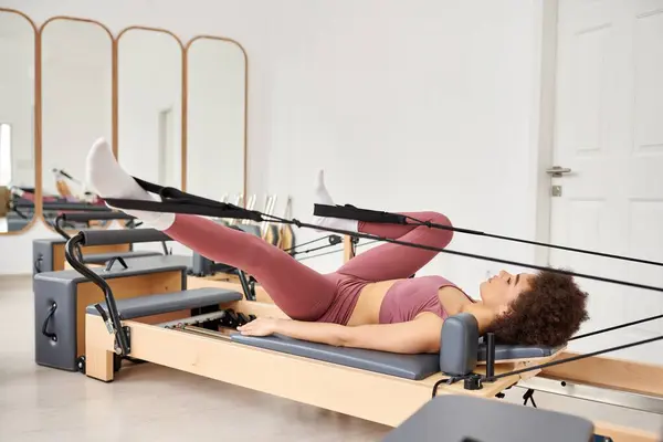 Sportliche Frau führt während einer Pilates-Stunde anmutig Übungen aus. — Stockfoto