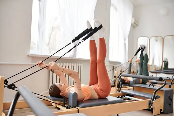 Mulher bonita graciosamente executa exercícios durante uma lição de pilates. — Fotografia de Stock