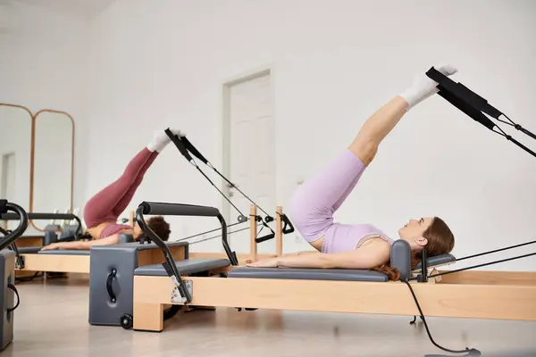 Deportiva mujer con gracia pivotando en una máquina de remo durante la lección de pilates. - foto de stock