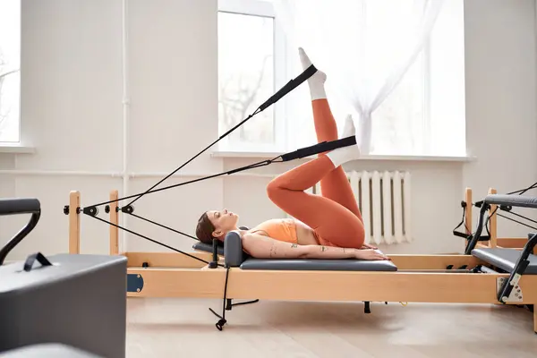 Ajuste a mulher graciosamente executa exercícios durante uma lição de pilates. — Fotografia de Stock