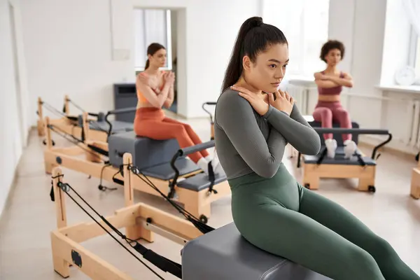 Las mujeres deportivas se concentran intensamente en su lección de Pilates mientras están en un gimnasio. - foto de stock