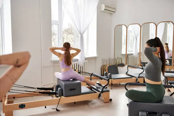 Sporty women performing dynamic exercises in a lively gym setting. — Stock Photo